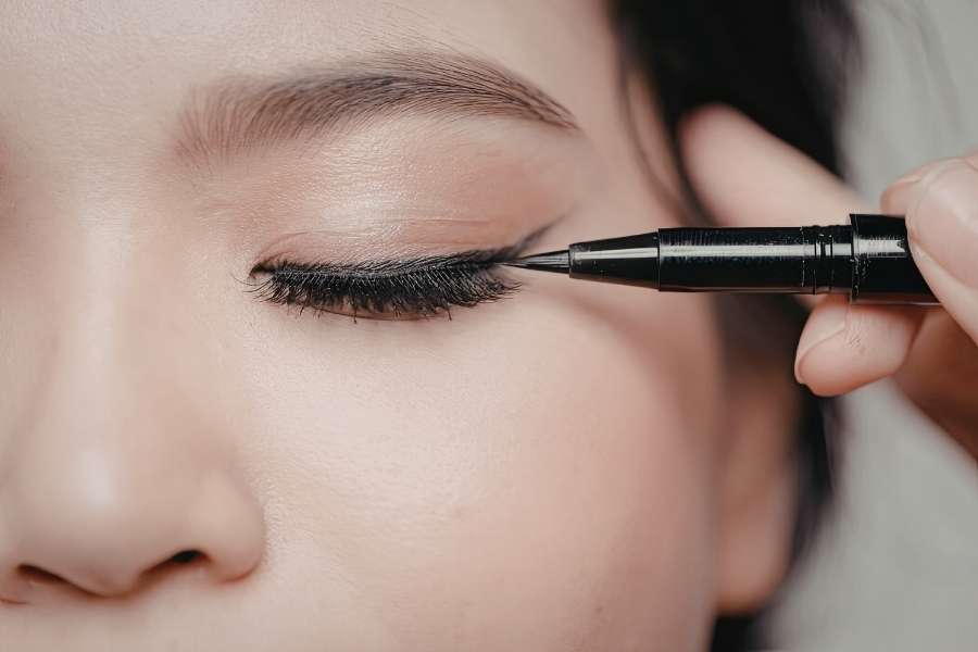 Application d'un trait d'eyeliner parfait sur la paupière avec un feutre noir.