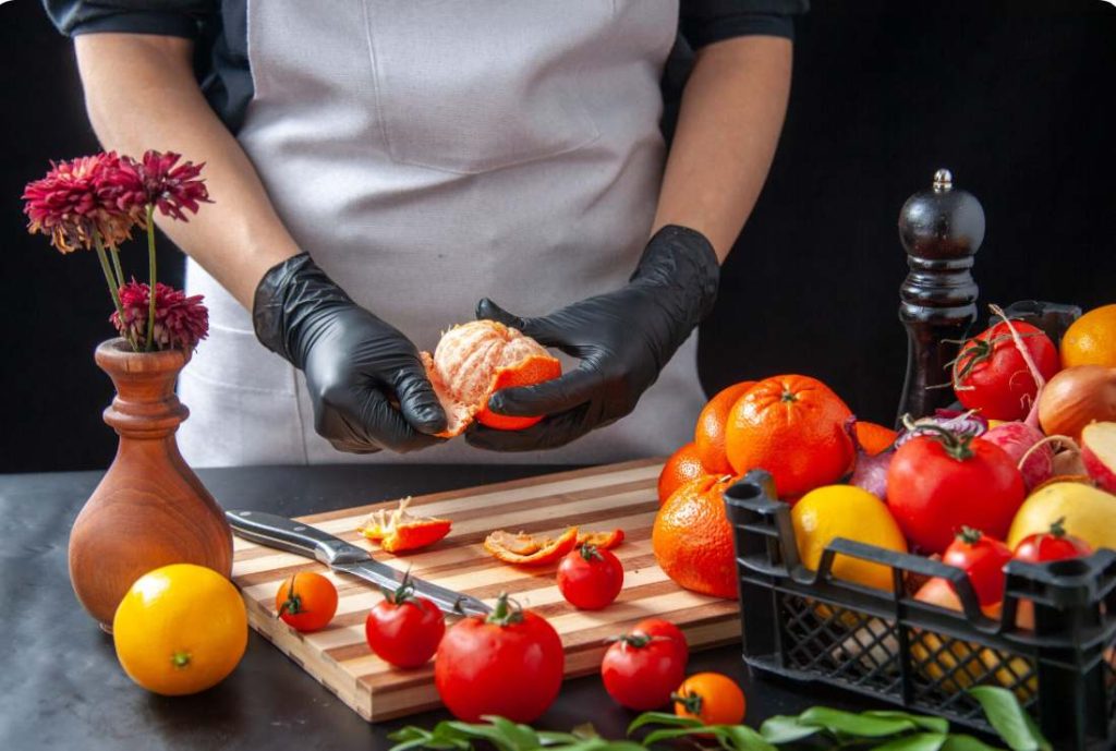 Chef préparant des agrumes et des légumes frais de saison pour un traiteur bio et local pour mariage.