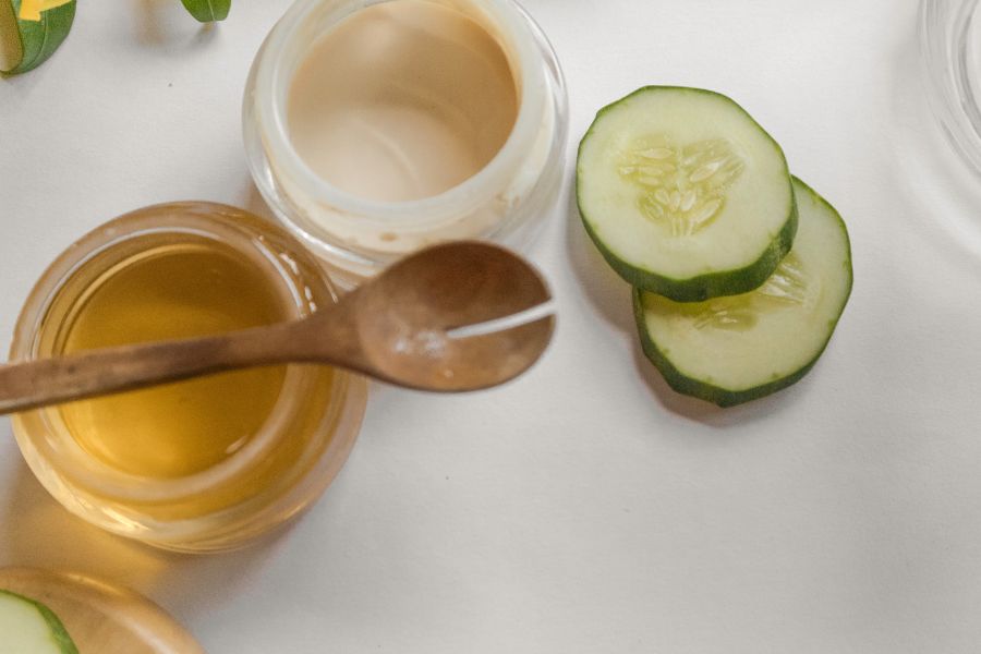 Des tranches de concombre frais et des petits pots de crème naturelle disposés sur une table claire.